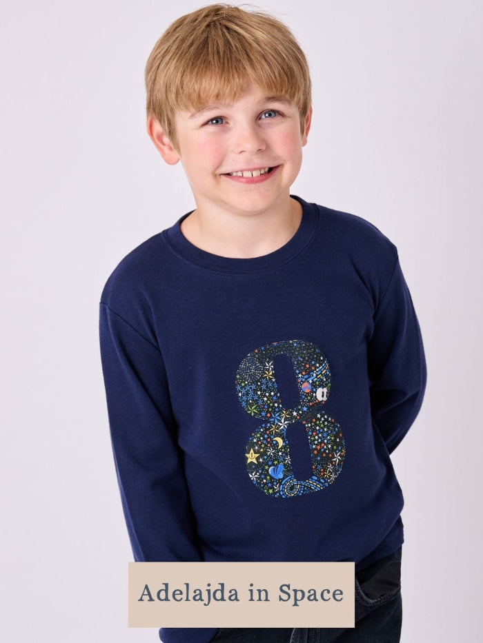 A smiling boy wearing a navy cotton t-shirt with the number 8 on the front cut from space liberty print