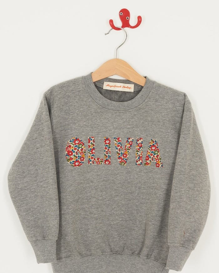 a grey kids personalised sweatshirt with her name on it cut from Betsy Ann Liberty print.