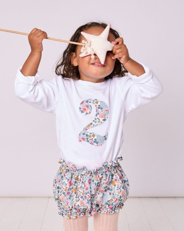 a 2 year old girl wearing a birthday kids white t-shirt with a number 2 cut from betsy grey liberty floral print on the front