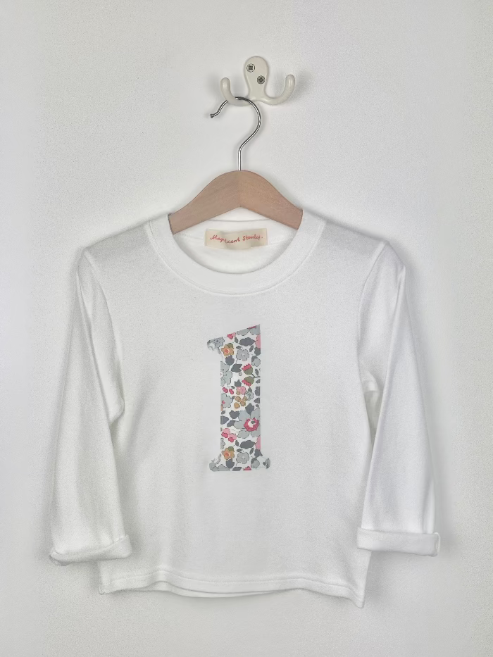 White long-sleeve shirt with a colourful Liberty betsy grey number '1' on a hanger against a white background