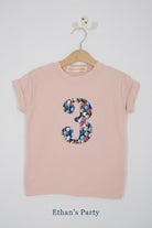 a pink 3rd birthday t-shirt with a number 3 cut from ethan's party balloon liberty floral print on the front