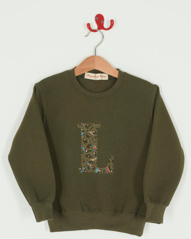 A khaki sweatshirt with an initial on the front. The initial is made from vintage cars Liberty print.