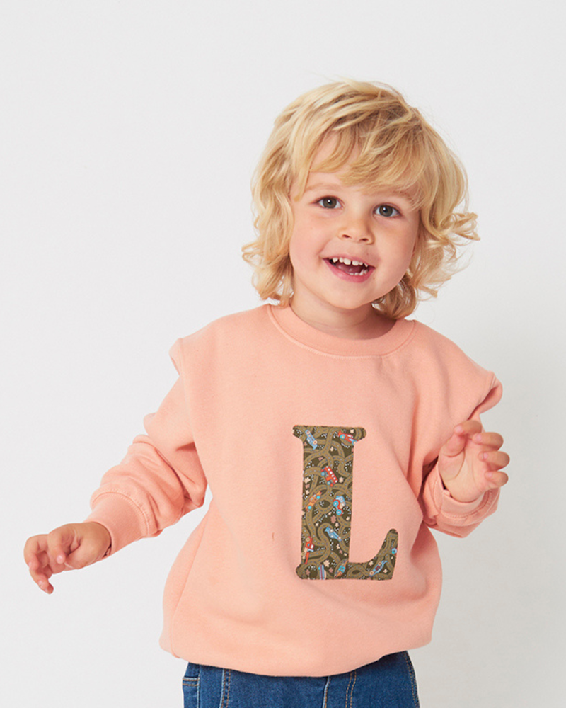 A pink personalised sweatshirt with an initial sewn on to the front. The initial is made from vintage car liberty print