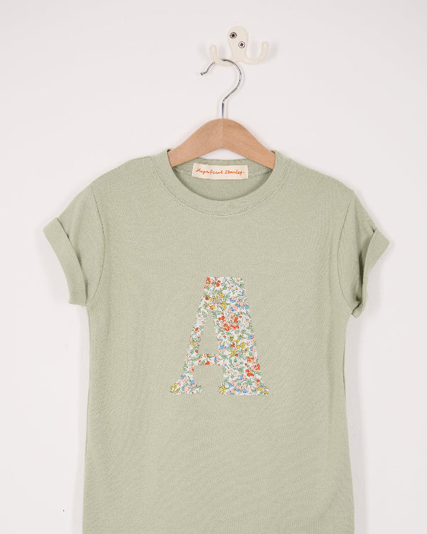 A personalised kids sage green t-shirt with his initial cut from nazanin liberty print on the front.