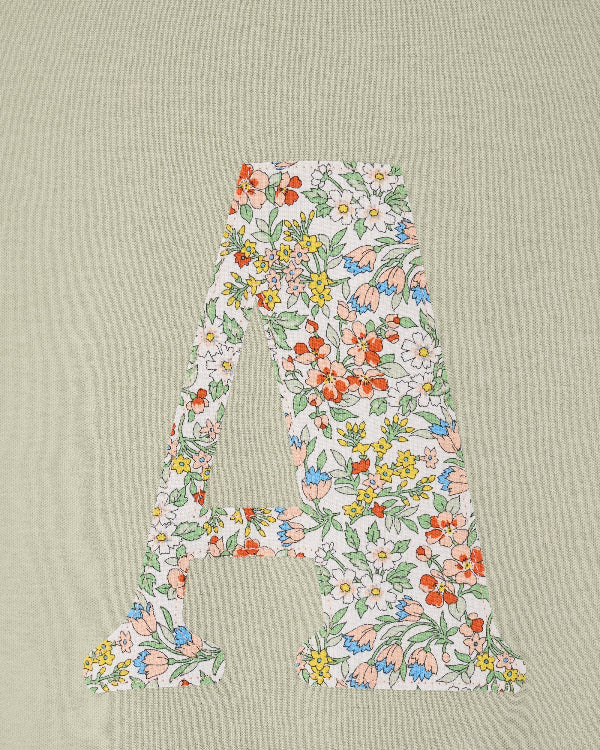 A personalised kids sage green t-shirt with his initial cut from Nazanin liberty print on the front.