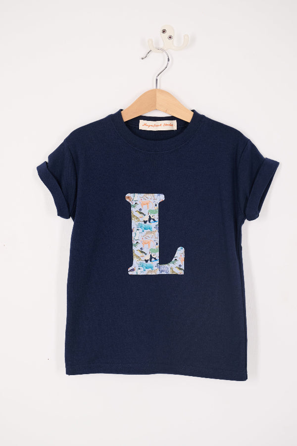 a personalised kids navy t-shirt with an initial cut from quey 2 zoo animal liberty print on the front.
