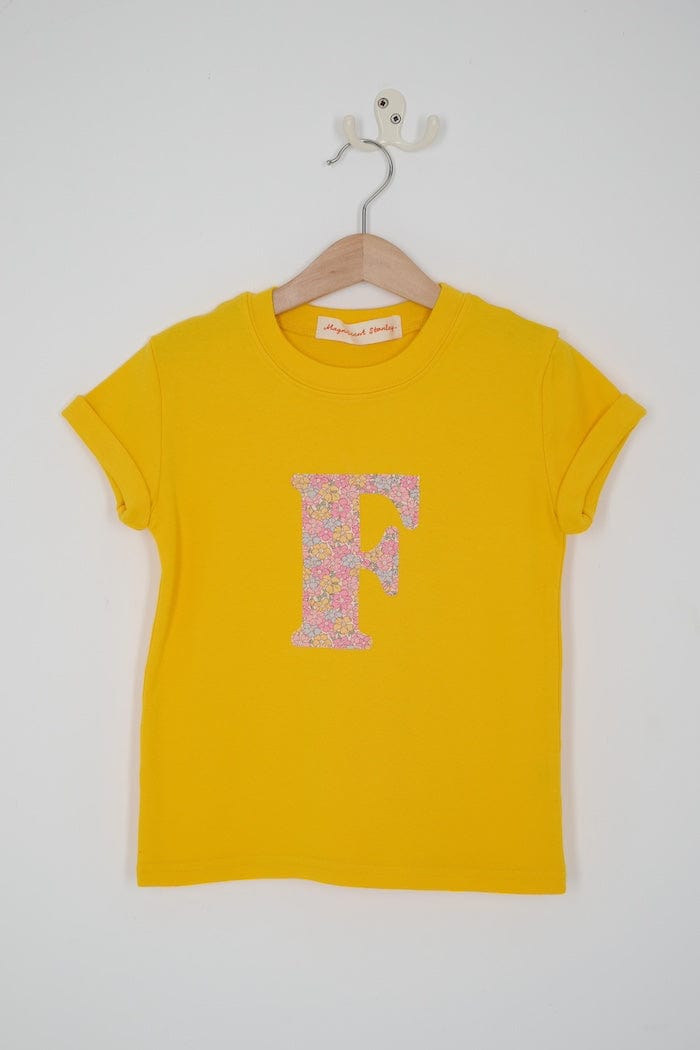 a personalised kids yellow t-shirt with an initial cut from sadie rose liberty floral print on the front