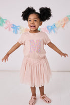 a little girl wearing a personalised kids pink t-shirt with an initial cut from sadie rose liberty floral print on the front