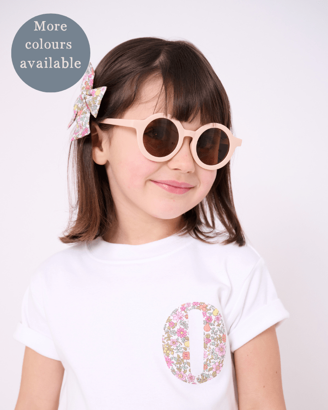 a 4 year old girl wearing a personalised white cotton kids t-shirt with a small initial on the front made from liberty print.