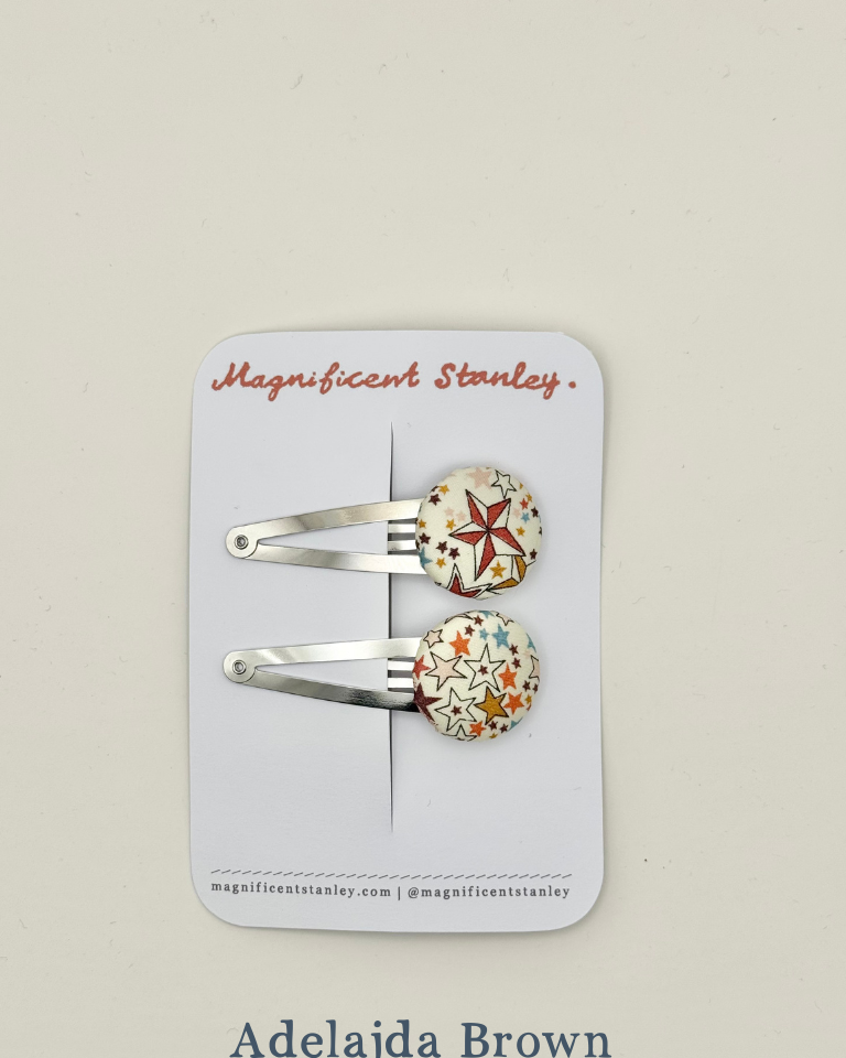 Two star print hair clips on a 'Magnificent Stanley' branded card in Adelajda Brown print