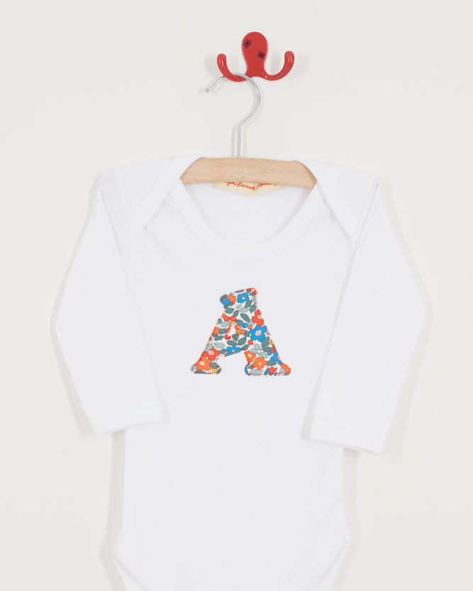 White baby onesie with colorful letter 'A' on a hanger against a white background