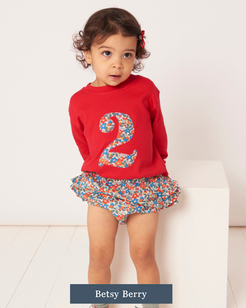 Child wearing a red t-shirt with a Liberty floral number 2 design and a matching skirt on a white background.