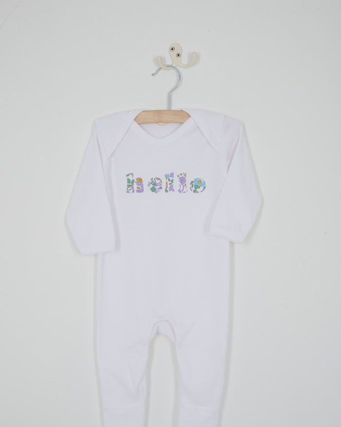 A white cotton baby bodysuit with the word hello made from Betsy Liberty Print sewn onto the front.