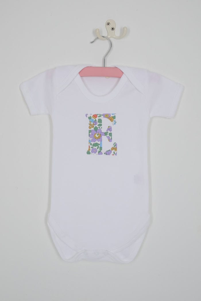 a personalised bodysuit baby grow with an initial cut from floral betsy purple Liberty print