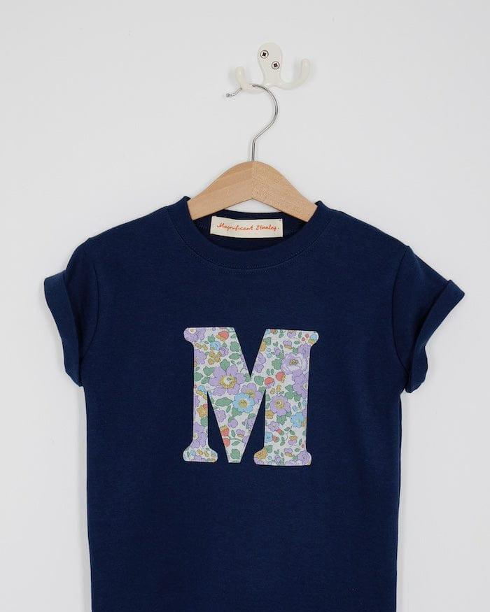 a personalised kids navy t-shirt with an initial cut from betsy purple liberty floral print on the front