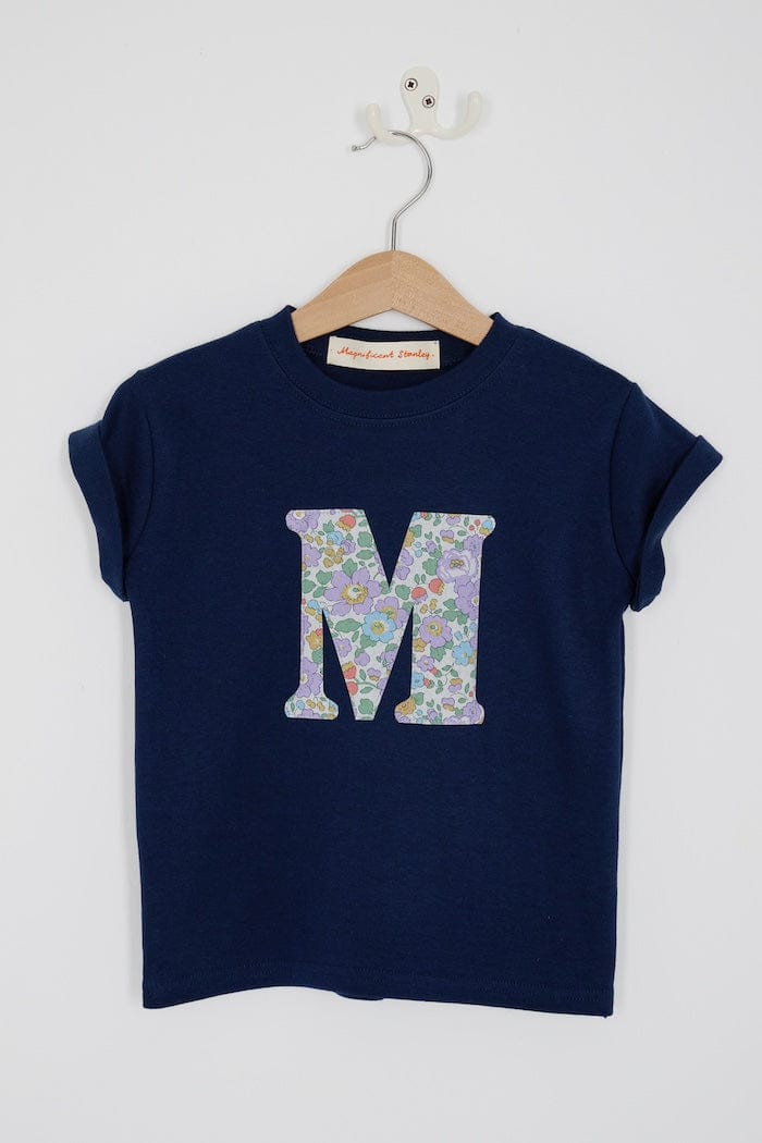 a personalised kids navy t-shirt with an initial cut from betsy purple liberty floral print on the front