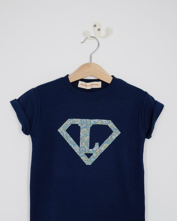 a personalised navy t-shirt with his initial inside a superhero emblem made from Liberty print