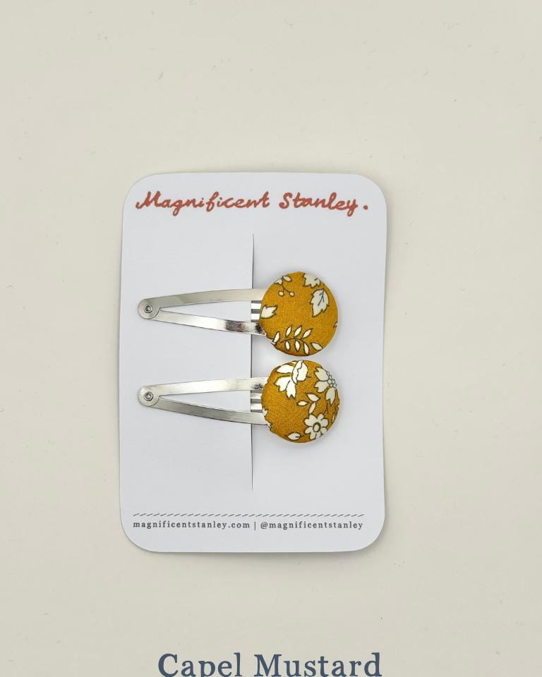 Pair of mustard yellow hair clips with floral liberty Capel mustard design on a 'Magnificent Stanley' card.