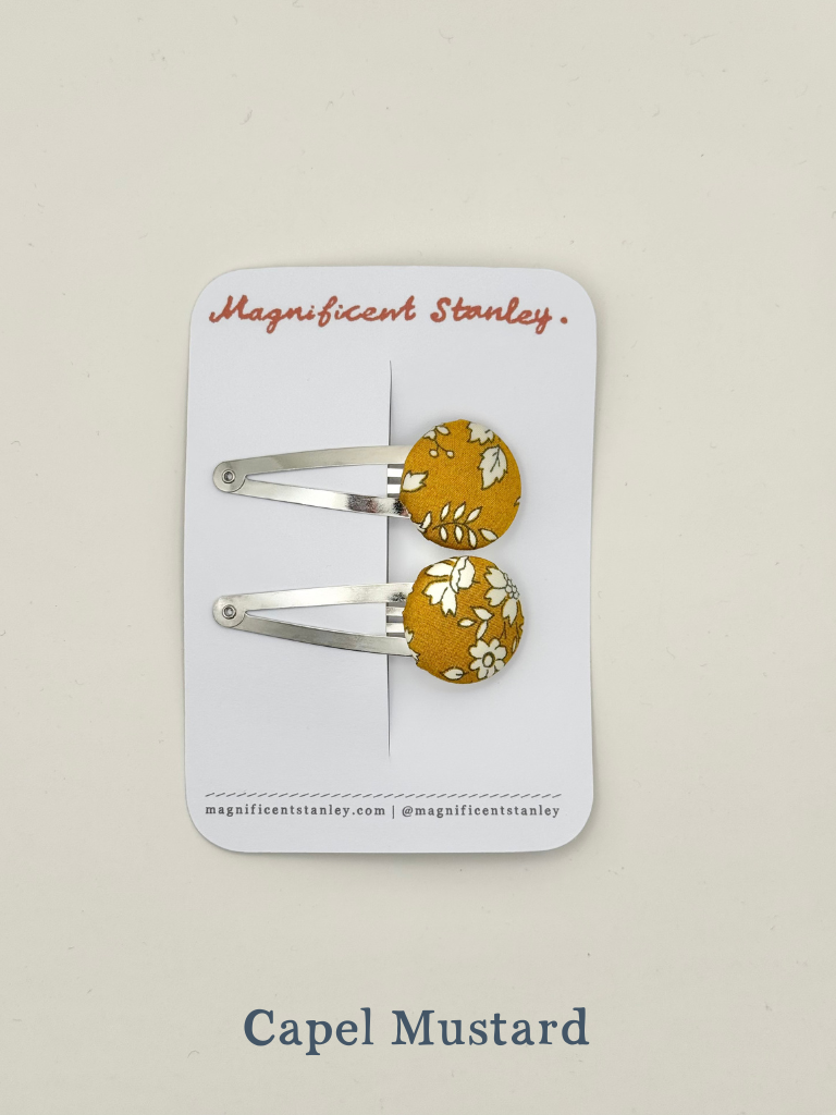 Pair of mustard yellow hair clips with floral liberty Capel mustard design on a 'Magnificent Stanley' card.
