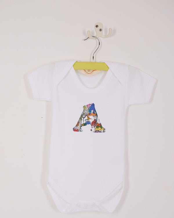 a personalised baby bodysuit with his initial cut from dinosaur liberty print on the front