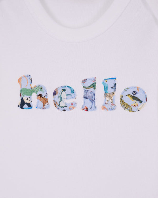 A close up of a white cotton babygrow with the word hello sewn on the front, cut from Quey 2 zoo animal Liberty print.