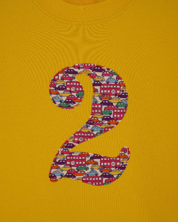 a yellow kids t-shirt with a number 3 cut from Hop on hop off red cars and london bus liberty print on the front.