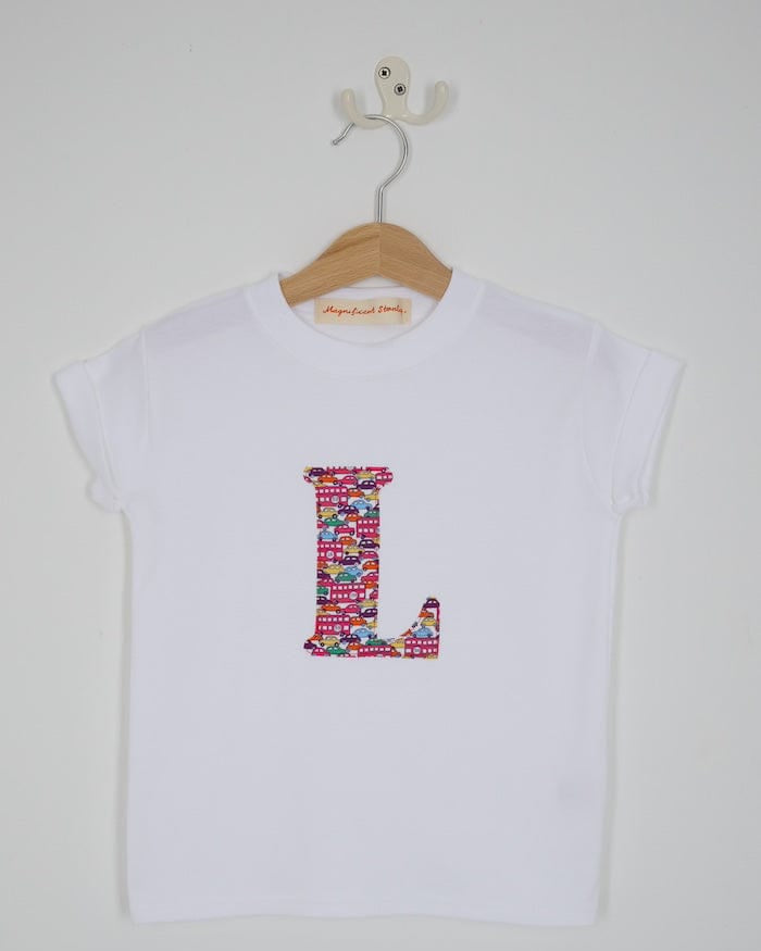a personalised kids white t-shirt with an initial cut from Hop on hop off red cars and london bus liberty print on the front
