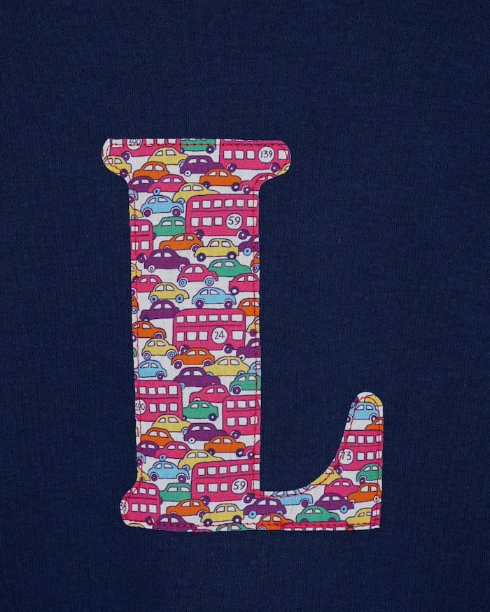 a navy cotton kids t-shirt with the letter 'L' personalised in a red Hop on hop off Liberty print. a close up of the stitching