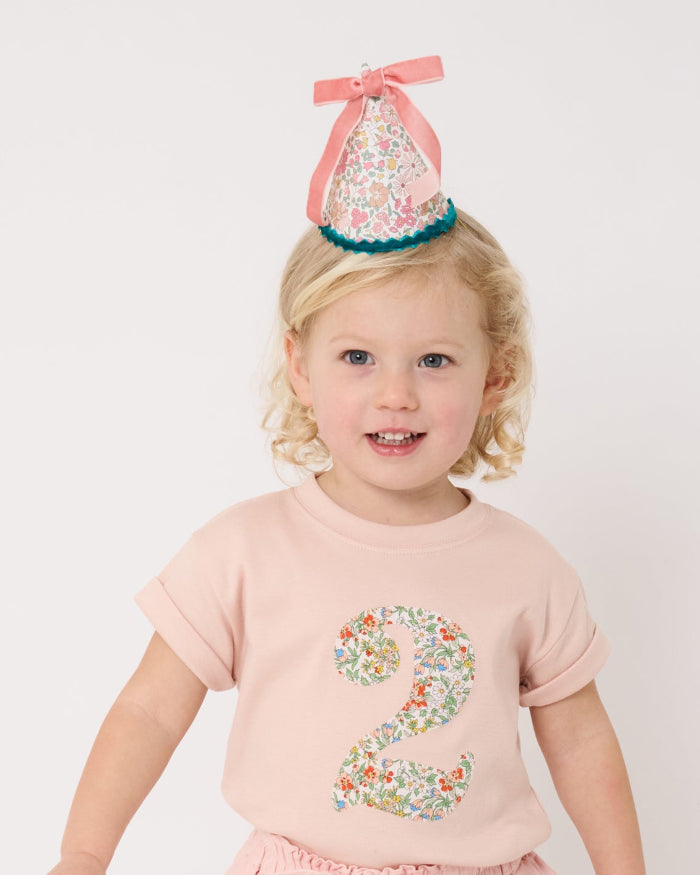 A birthday girl wearing a pale pink t-shirt with a Liberty Nazanin floral number '2' on the front.