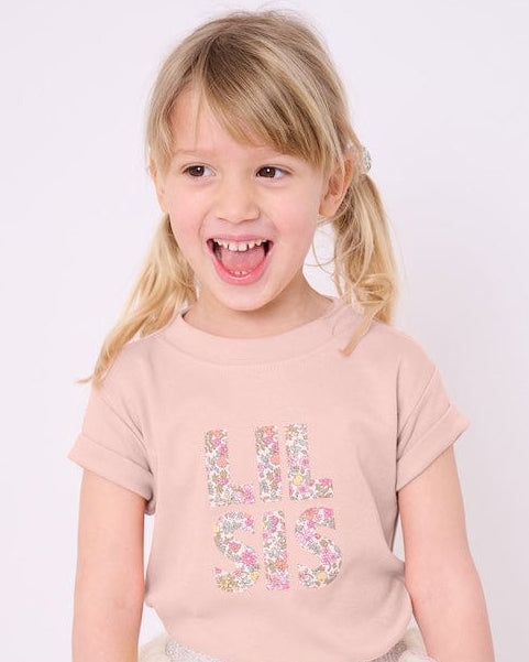Little sister wearing a pink t-shirt with the words Lil Sis on the front cut from floral Liberty print.