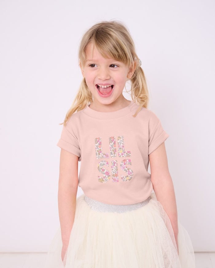 Little sister wearing a pink t-shirt with the words Lil Sis on the front cut from floral Liberty print.