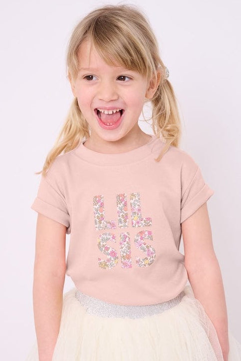 Little sister wearing a pink t-shirt with the words Lil Sis on the front cut from floral Liberty print.