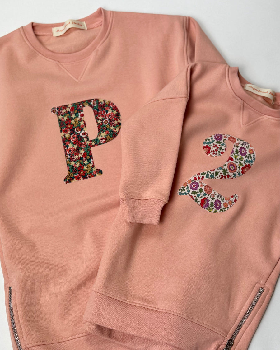 Pink sweatshirt dress with Liberty floral letter 'P' and 'E' on a white background