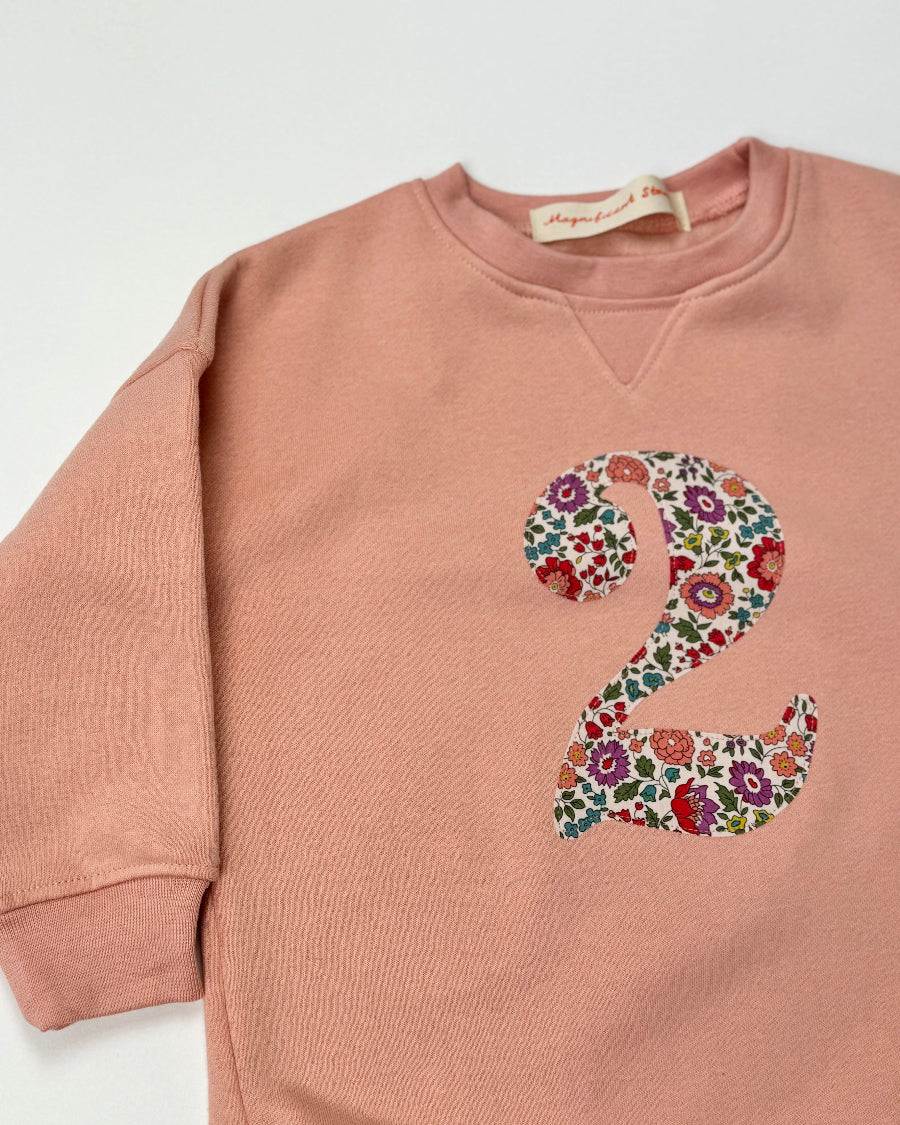 Pink sweatshirt with Liberty floral number '2' on a white background
