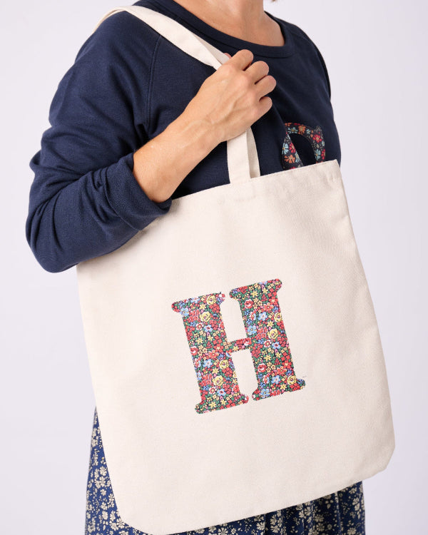A woman with a Canvas Tote Bag on her shoulder, personalised with her initial in Liberty ditsy floral fabric