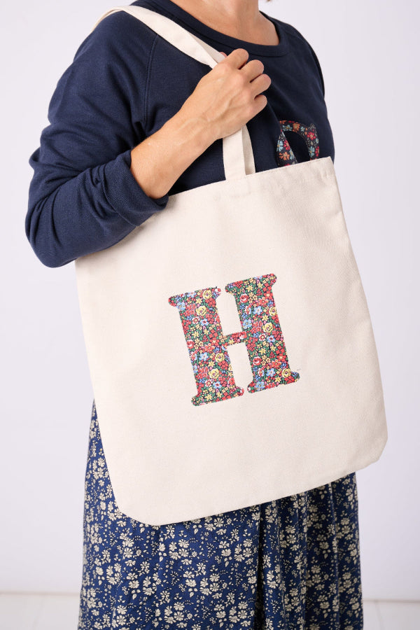 A woman with a Canvas Tote Bag on her shoulder, personalised with her initial in Liberty ditsy floral fabric