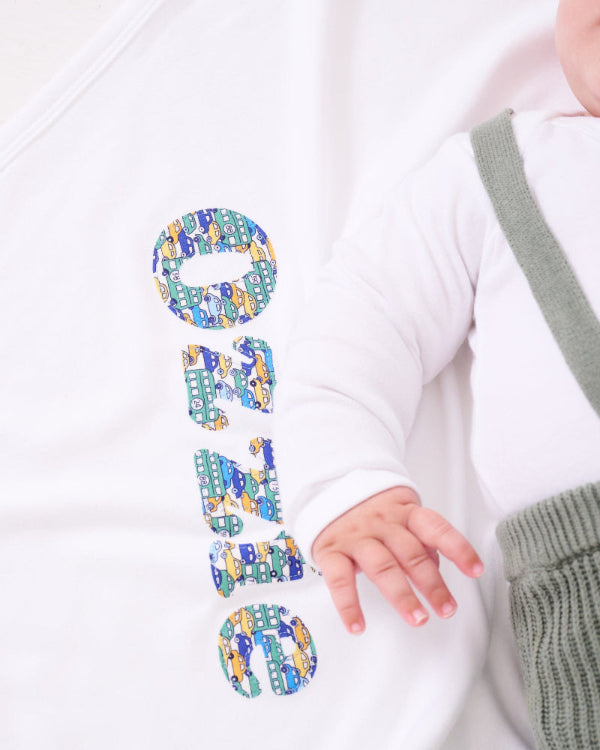 A new baby boy laying on a cotton baby Blanket personalised with his name in Liberty print