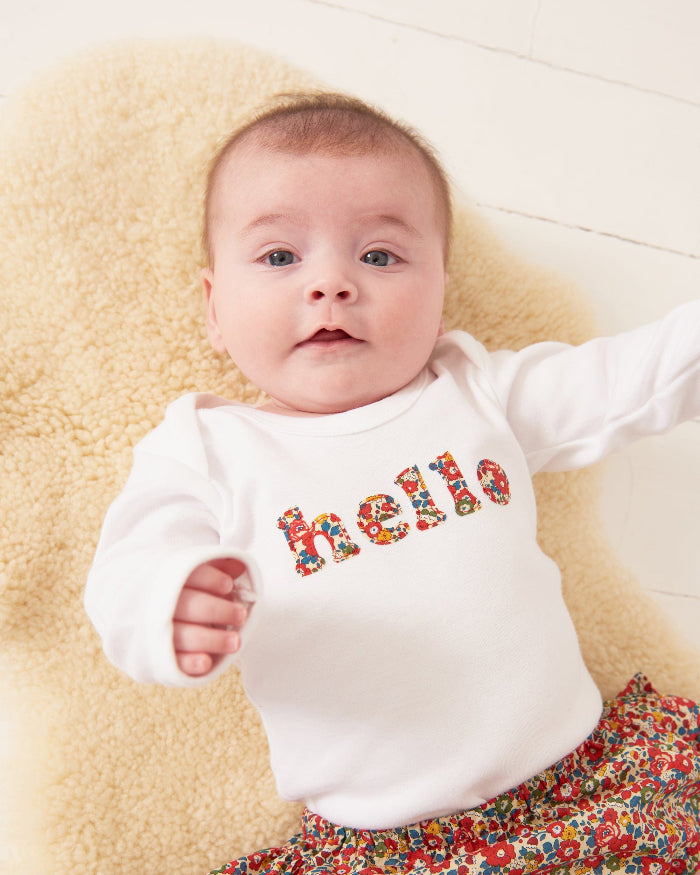 Magnificent Stanley Bodysuit 'hello' Bodysuit in choice of Liberty Print Magnificent Stanley Bodysuit 'hello' Bodysuit. New baby wears a white bodysuit with the word hello on it. the letters are cut from floral liberty print