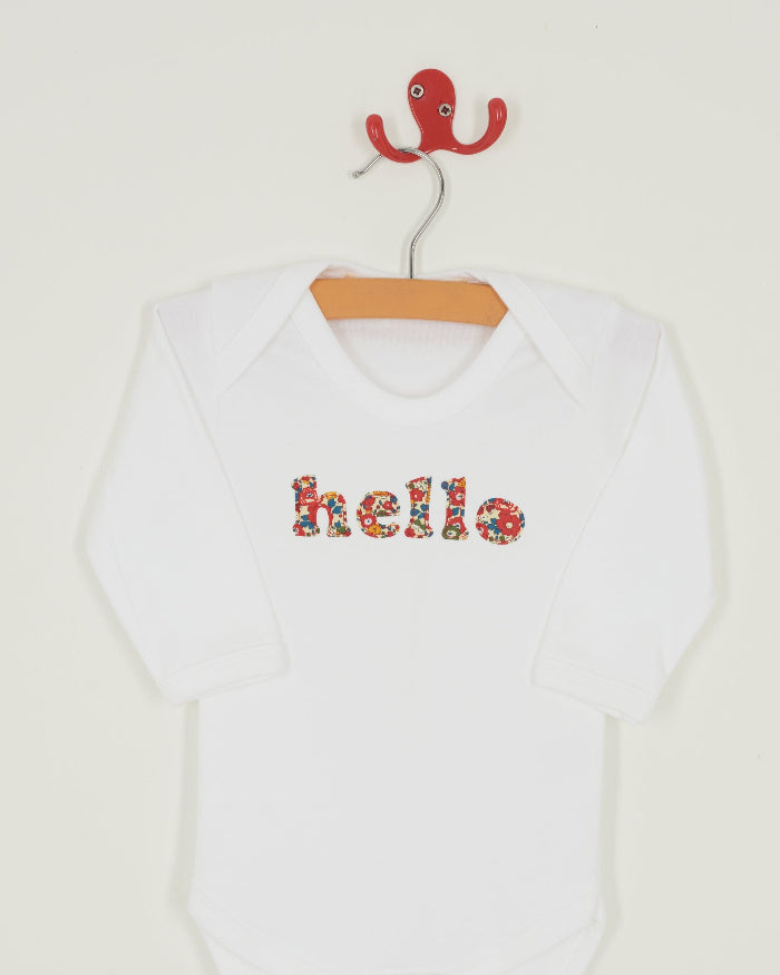 Magnificent Stanley Bodysuit 'hello' Bodysuit in choice of Liberty PrintMagnificent Stanley Bodysuit 'hello' Bodysuit. A white bodysuit with the word hello on it. the letters are cut from floral liberty print