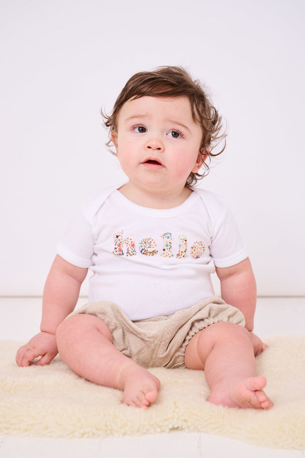 Magnificent Stanley Bodysuit 'hello' Bodysuit. New baby wears a white bodysuit with the word hello on it. the letters are cut from starry liberty print