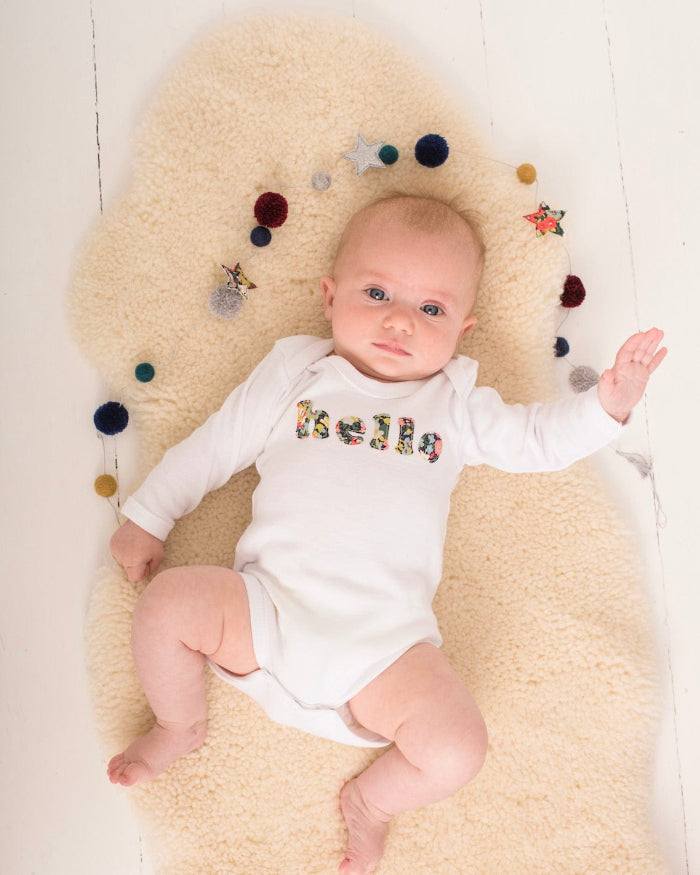 Magnificent Stanley Bodysuit 'hello' Bodysuit in choice of Liberty Print Magnificent Stanley Bodysuit 'hello' Bodysuit. New baby wears a white bodysuit with the word hello on it. the letters are cut from floral liberty print