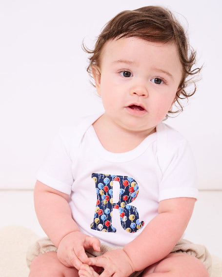 A baby wearing a Personalised Bodysuit in Ethan's Party Liberty Print