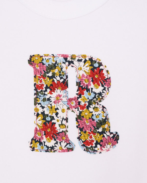 A close up of the letter and stitching on a Personalised initial baby Bodysuit in Libby floral Liberty Print.