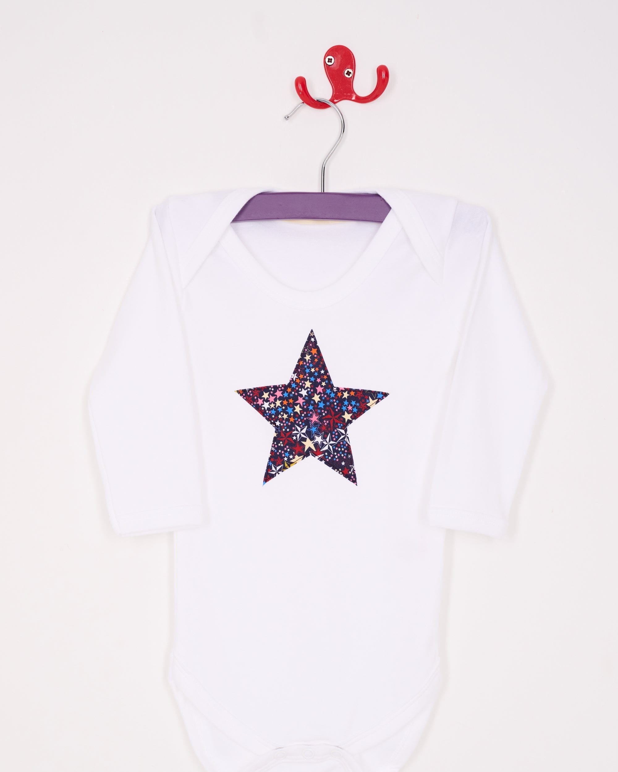 A white bodysuit babygrow with a Liberty Adelajda's Wish print festive star sewn on the front.