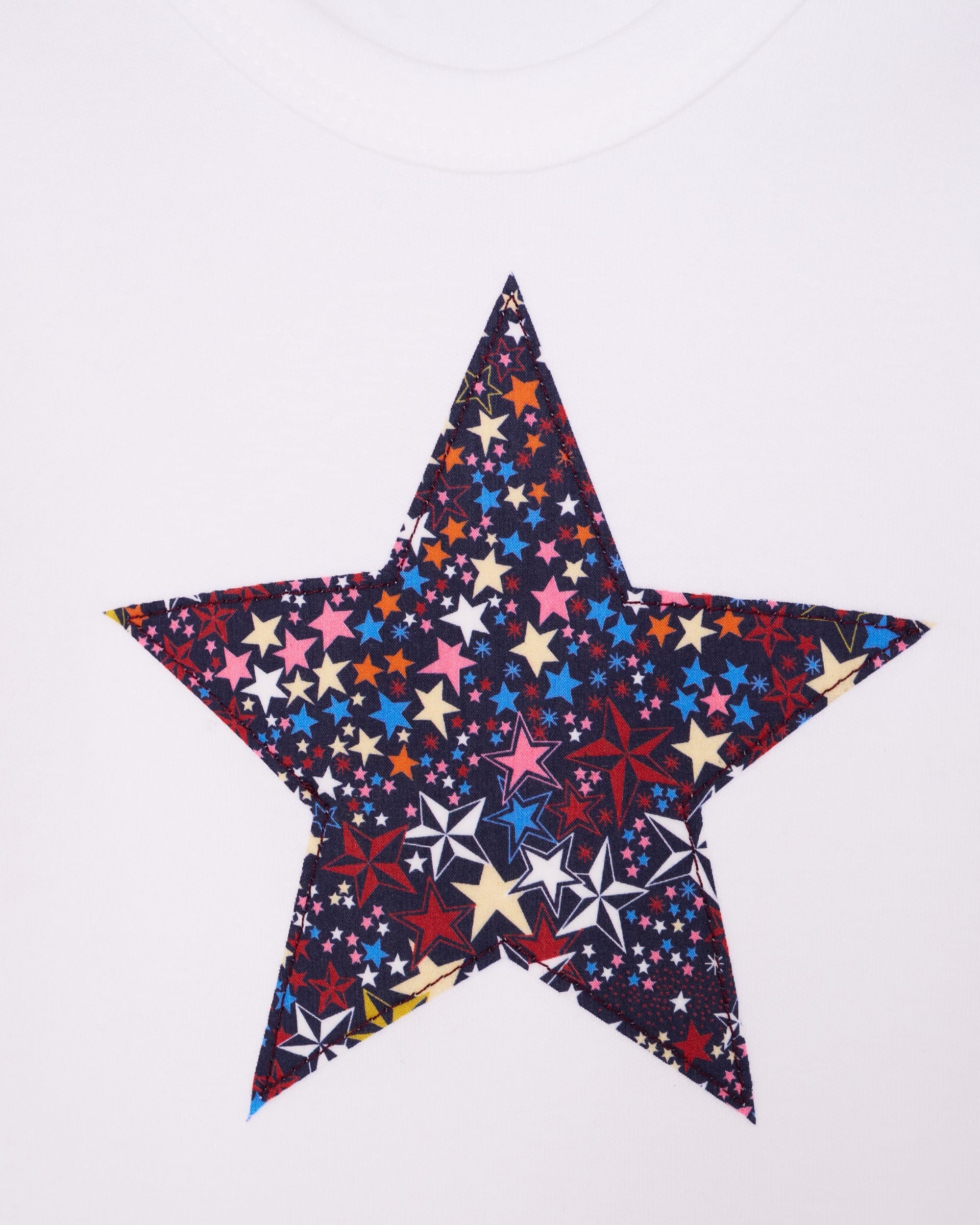 A close up of the appliqué white bodysuit babygrow with a Liberty Adelajda's Wish print festive star sewn on the front.