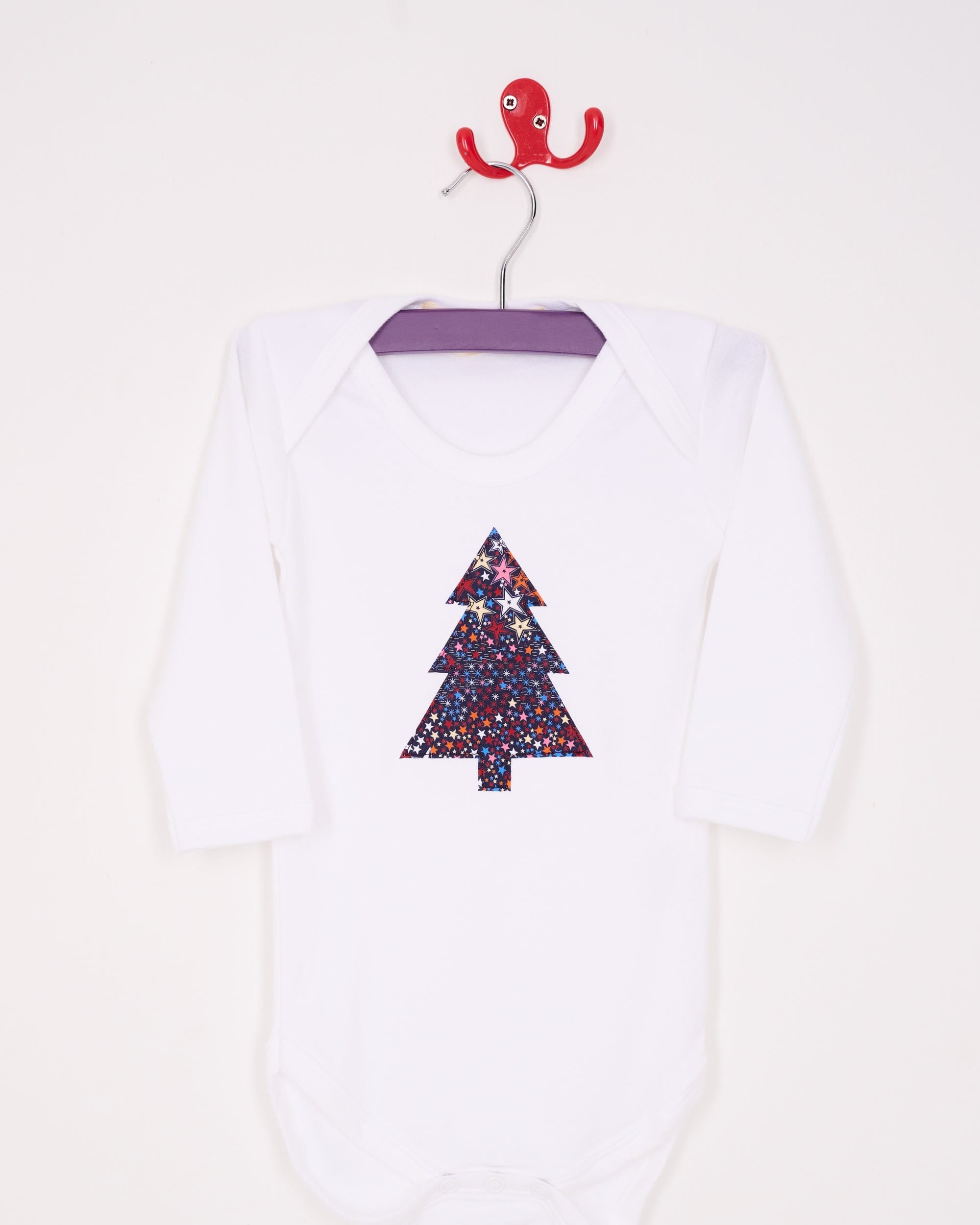 A white bodysuit babygrow with a Liberty Adelajda's Wish print Christmas tree sewn on the front.