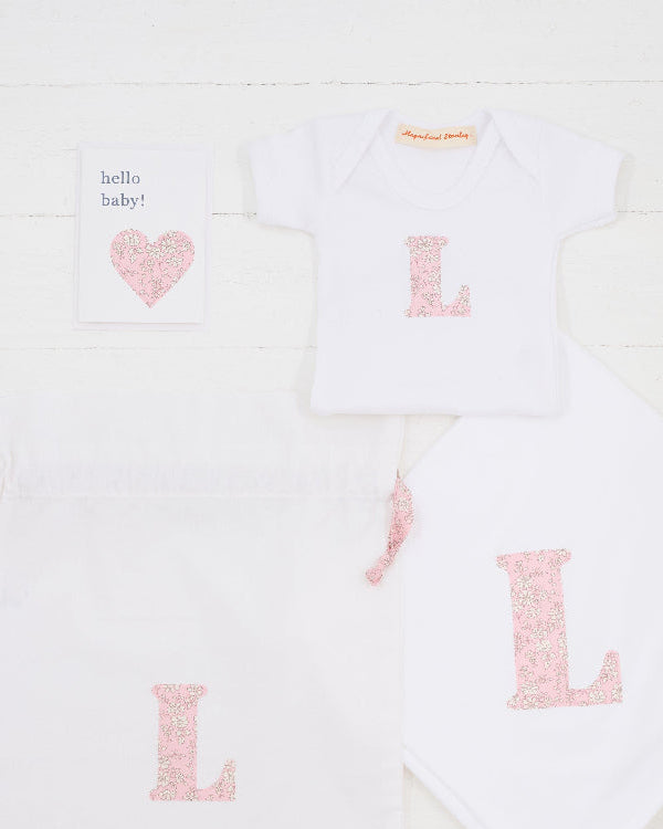 a personalised baby gift set consisting of a hello baby card, a personalised bodysuit, personalised cotton baby blanket and a gift bag, all personalised with Liberty print.