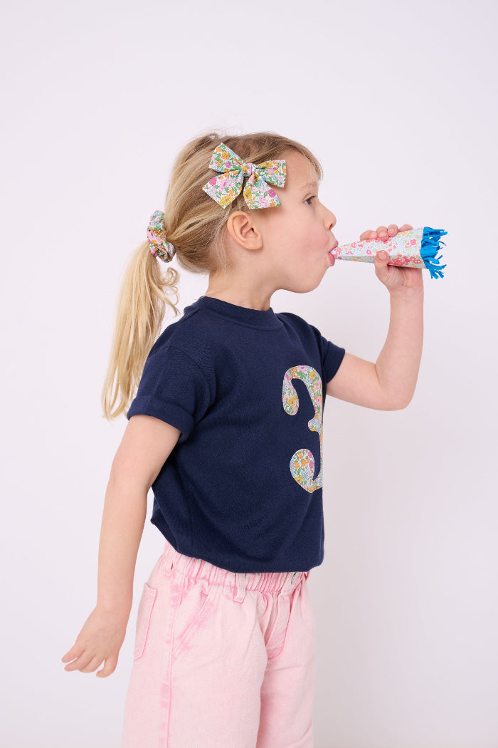 a ittle girl wearing a Magnificent Stanley Scrunchie made from tana lawn cotton Liberty Print in her hair