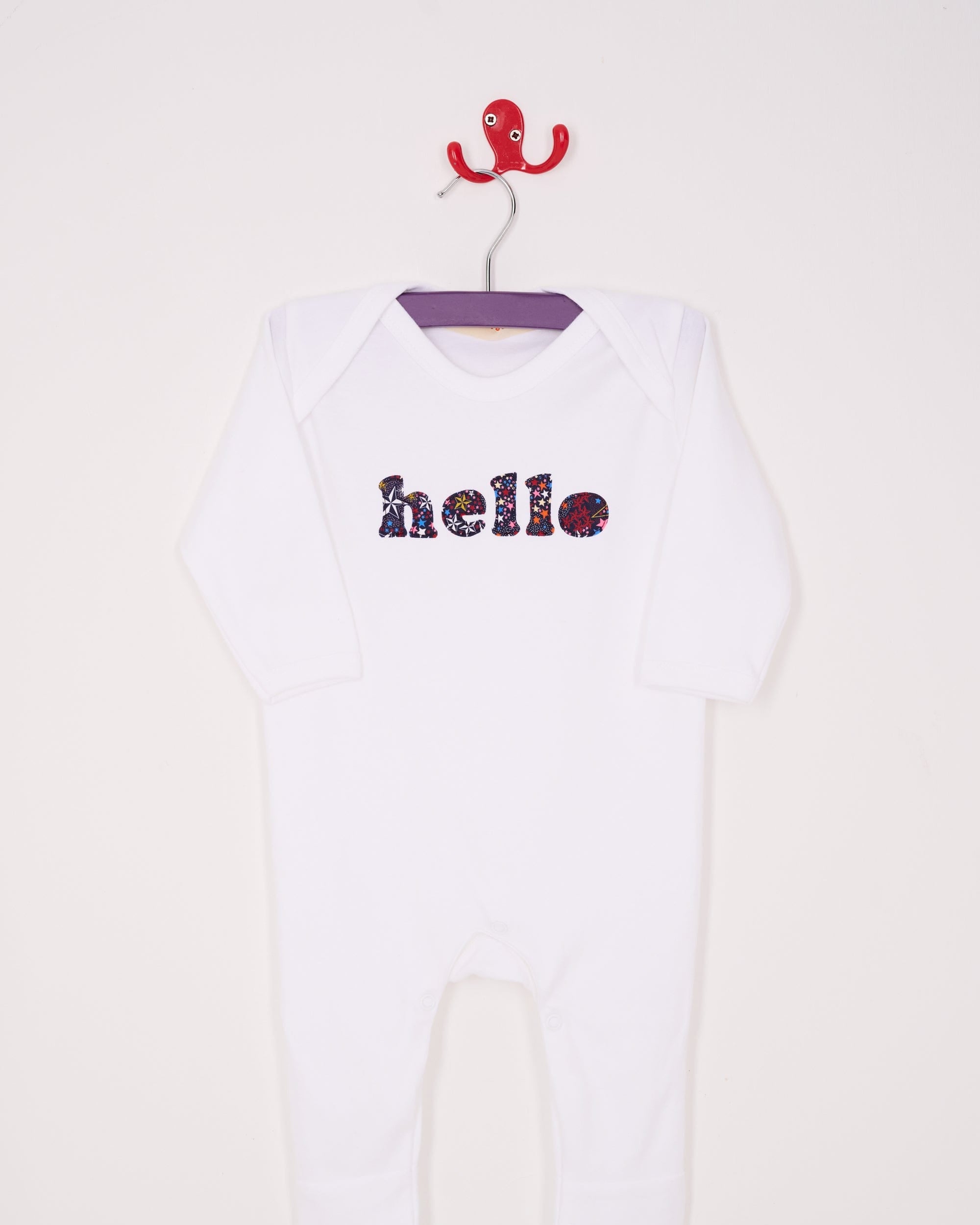 a white cotton romper with the word hello on it. the letters are cut from starry liberty print