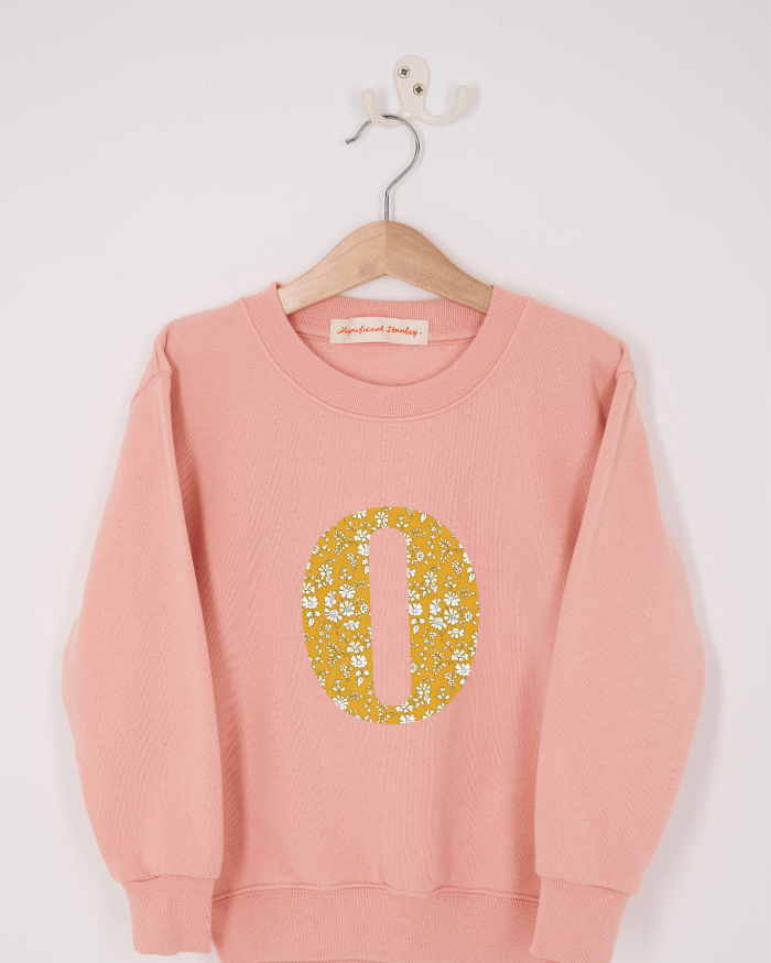 A pink personalised sweatshirt with an initial sewn on to the front. The initial is made from floral Capel liberty print